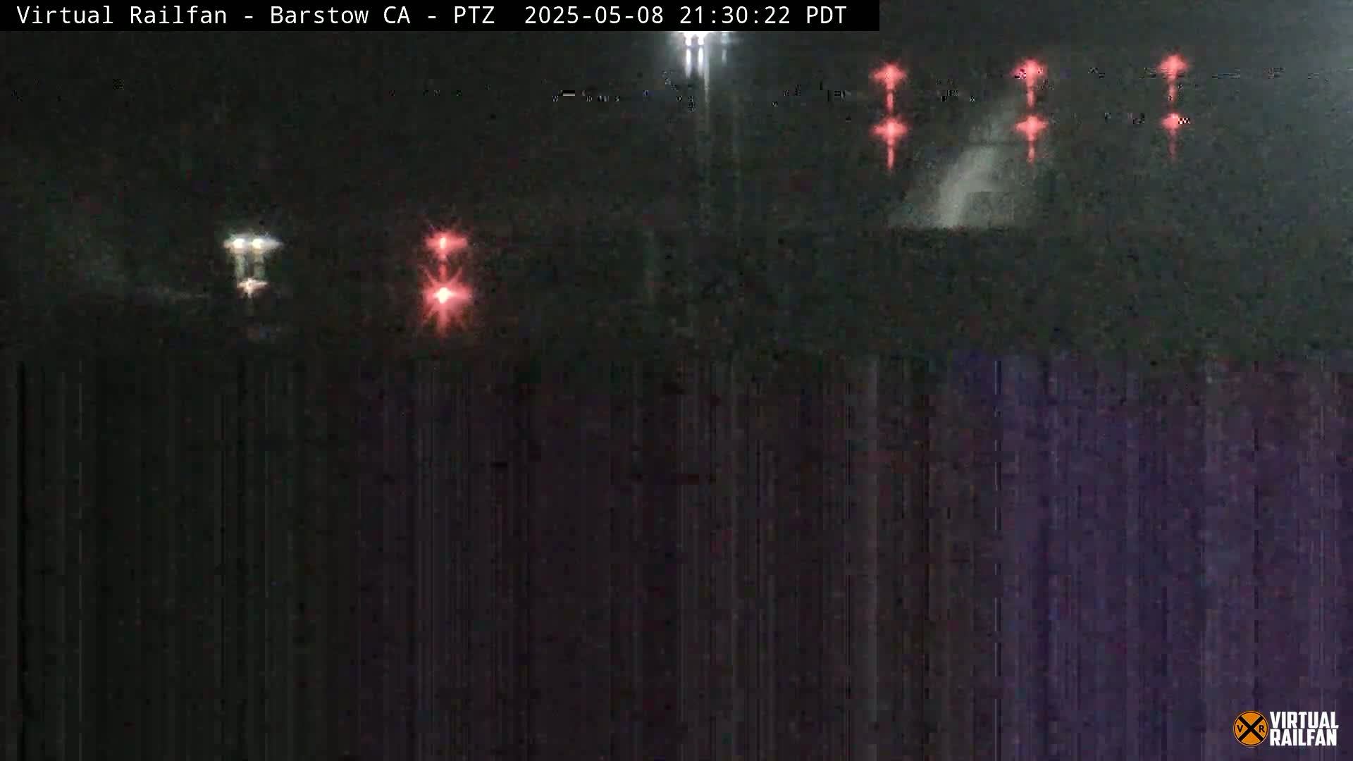 At night, a nighttime scene shows distant lights from what appears to be a train, possibly in motion, and several red lights possibly indicating signals or other equipment.