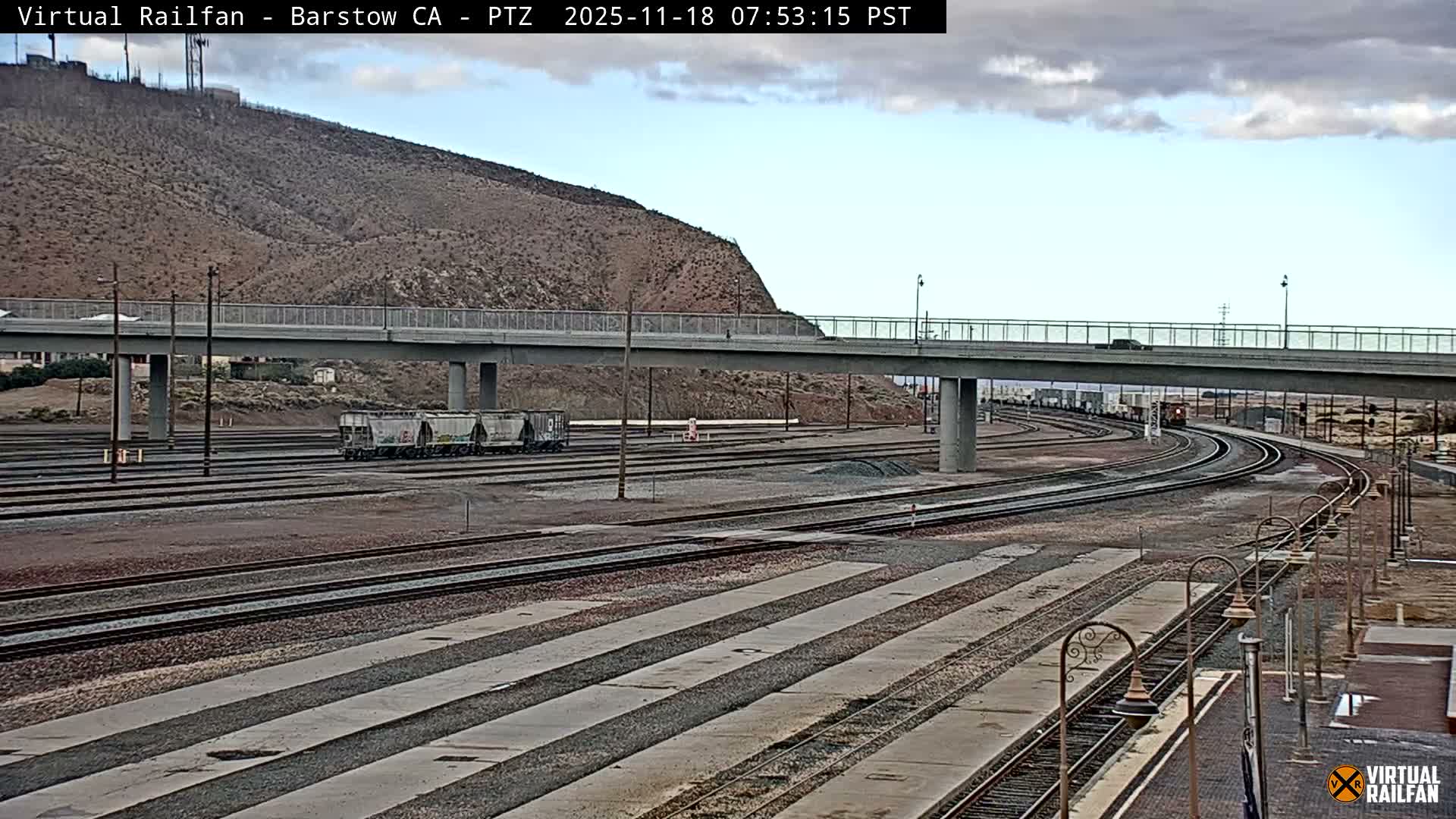 A nighttime view of a flat, dark expanse of land with parallel lines, a small piece of machinery, and distant lights under a clear, dark sky.