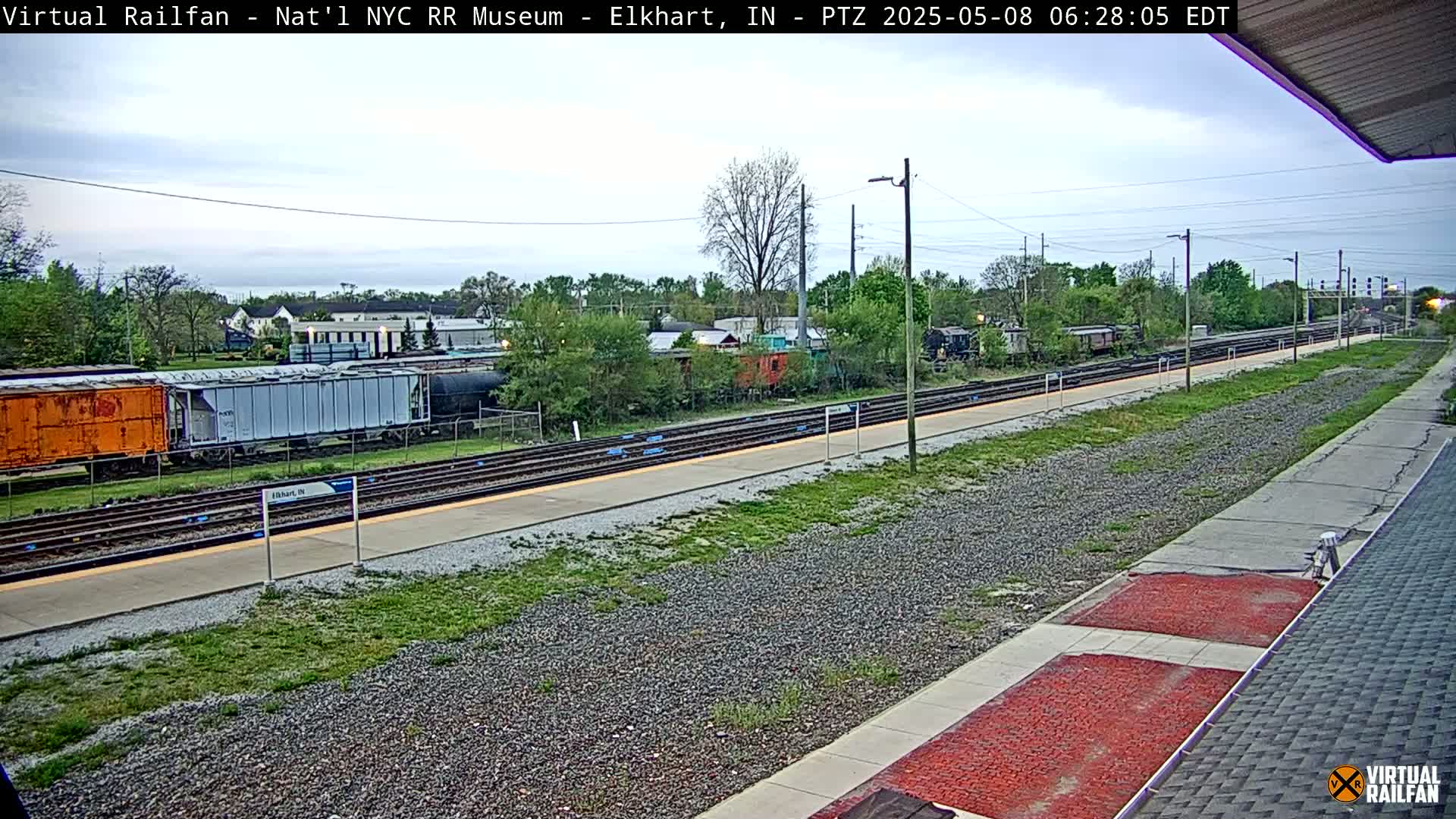 A train platform with several railcars and a cloudy sky.