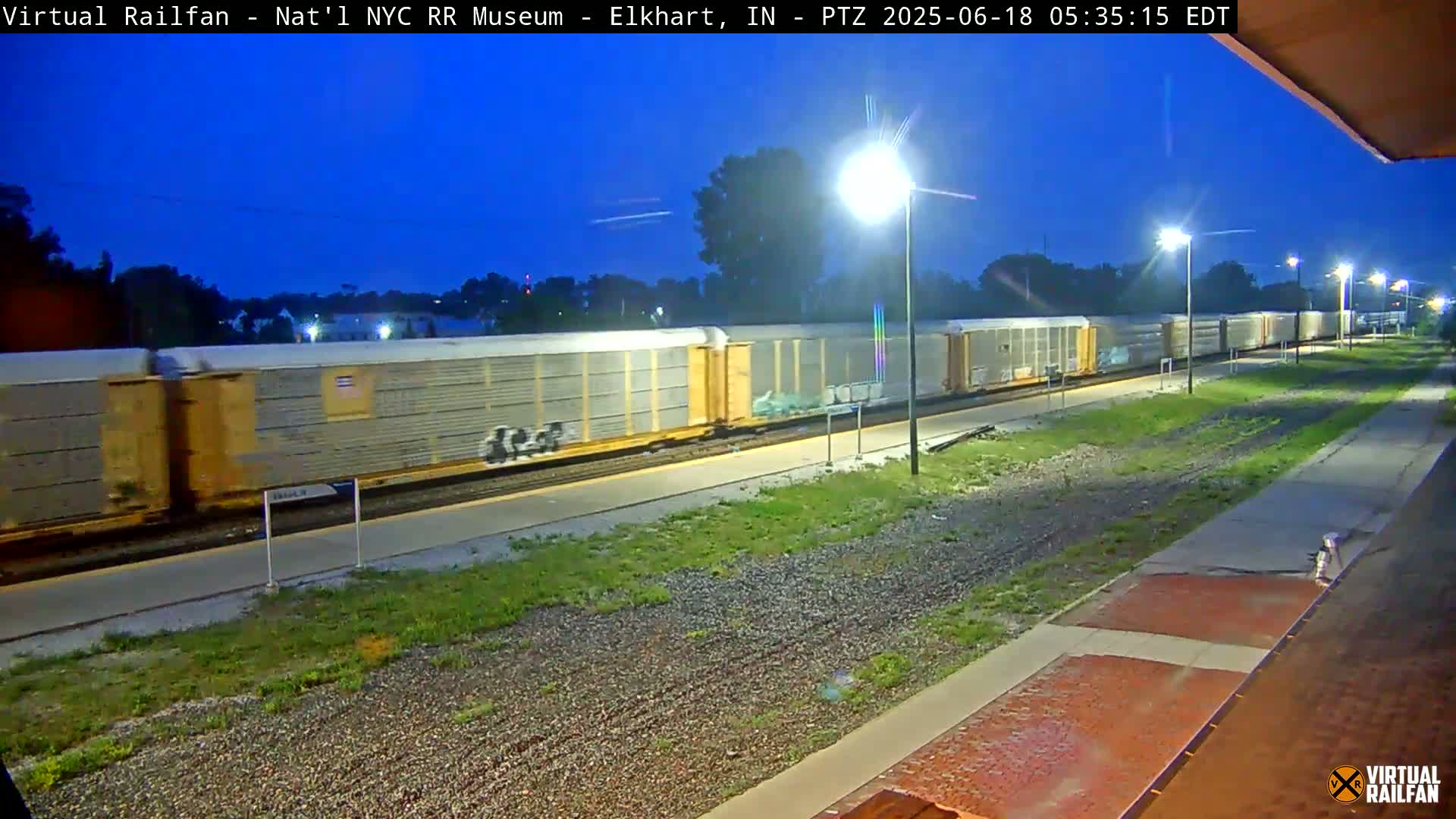 A long freight train passes by under a twilight sky.