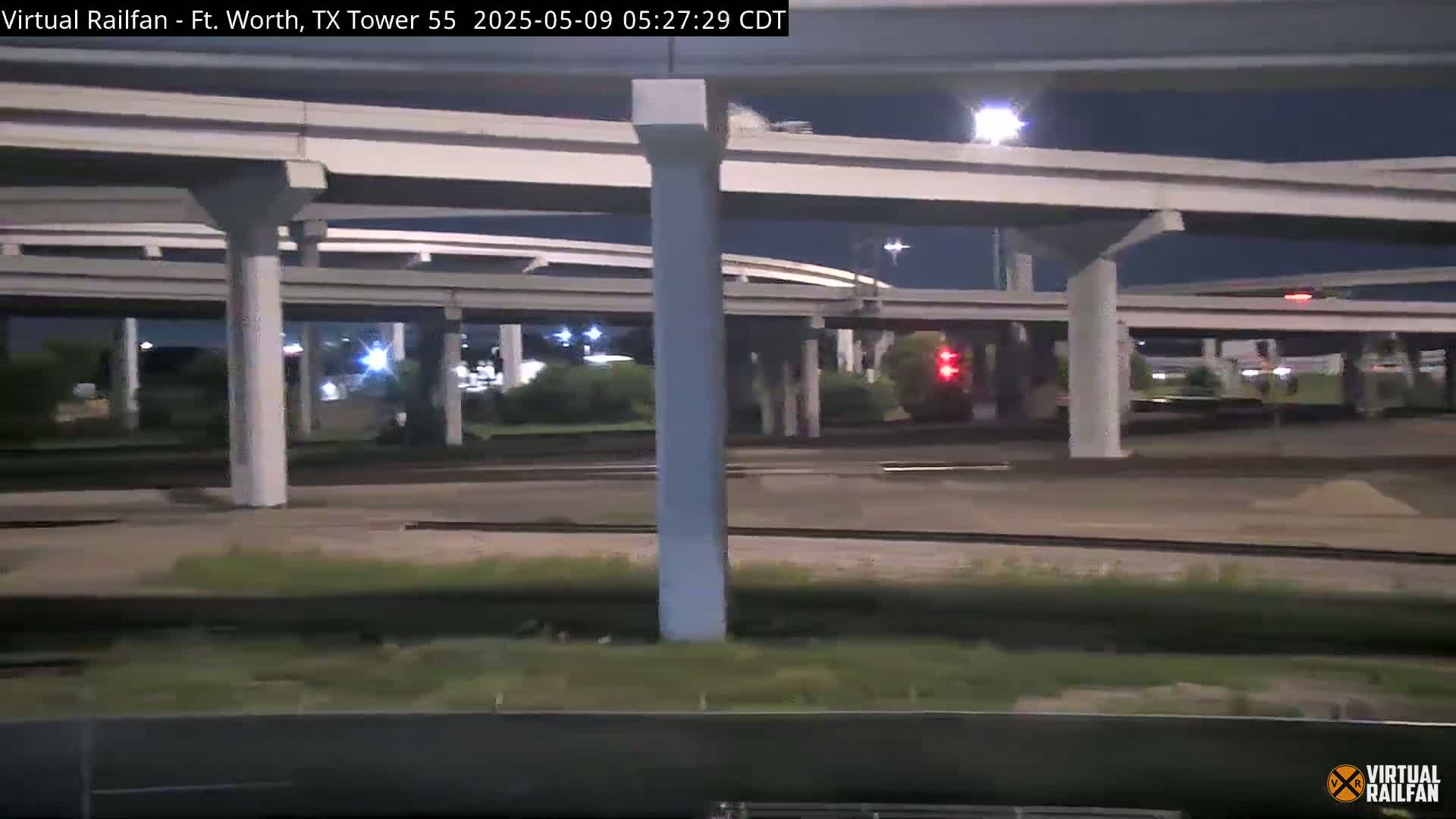 A nighttime view of an elevated highway interchange with train tracks below.
