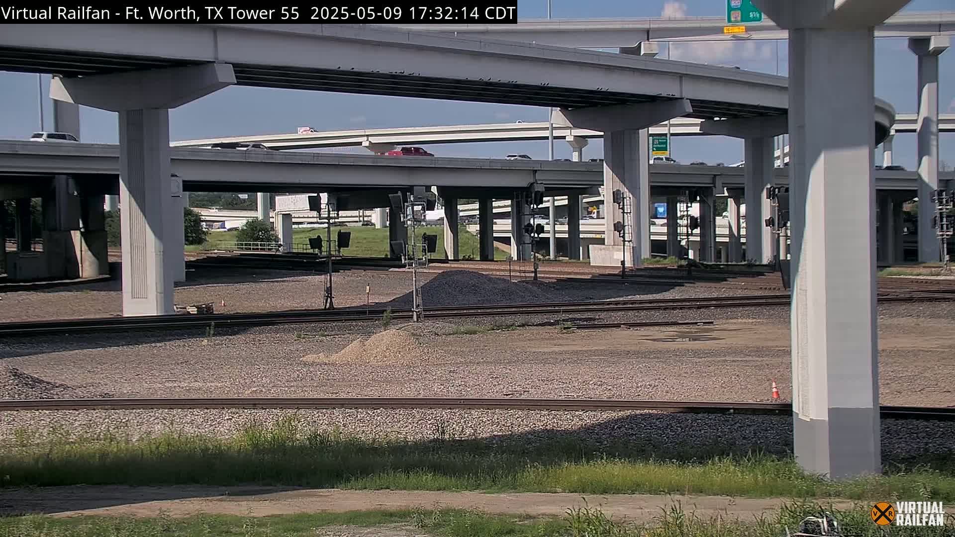 A view of a highway overpass and railroad tracks on a partly sunny day.