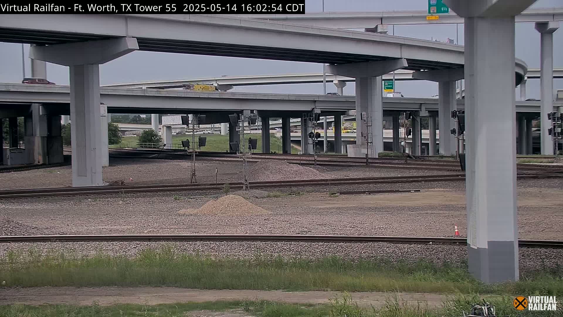 Railroad tracks and a large highway overpass under an overcast sky.