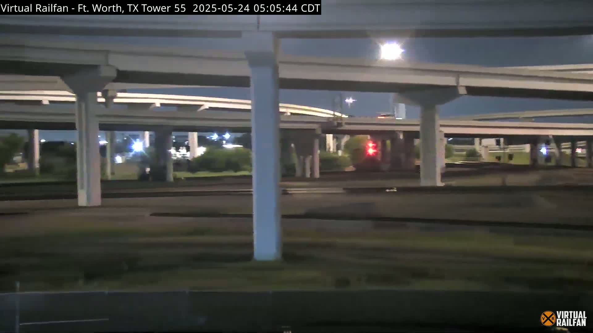 A nighttime view of a highway interchange with several overpasses and minimal traffic under partly cloudy skies.