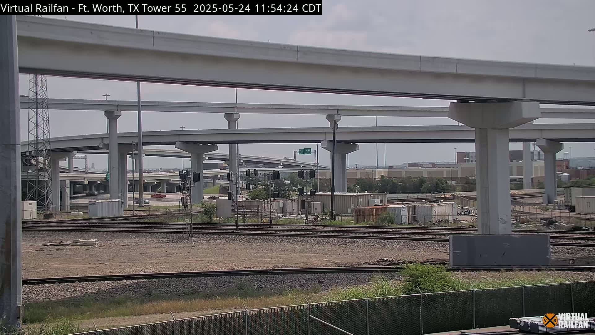 A view of railroad tracks beneath a complex overpass system on an overcast day.