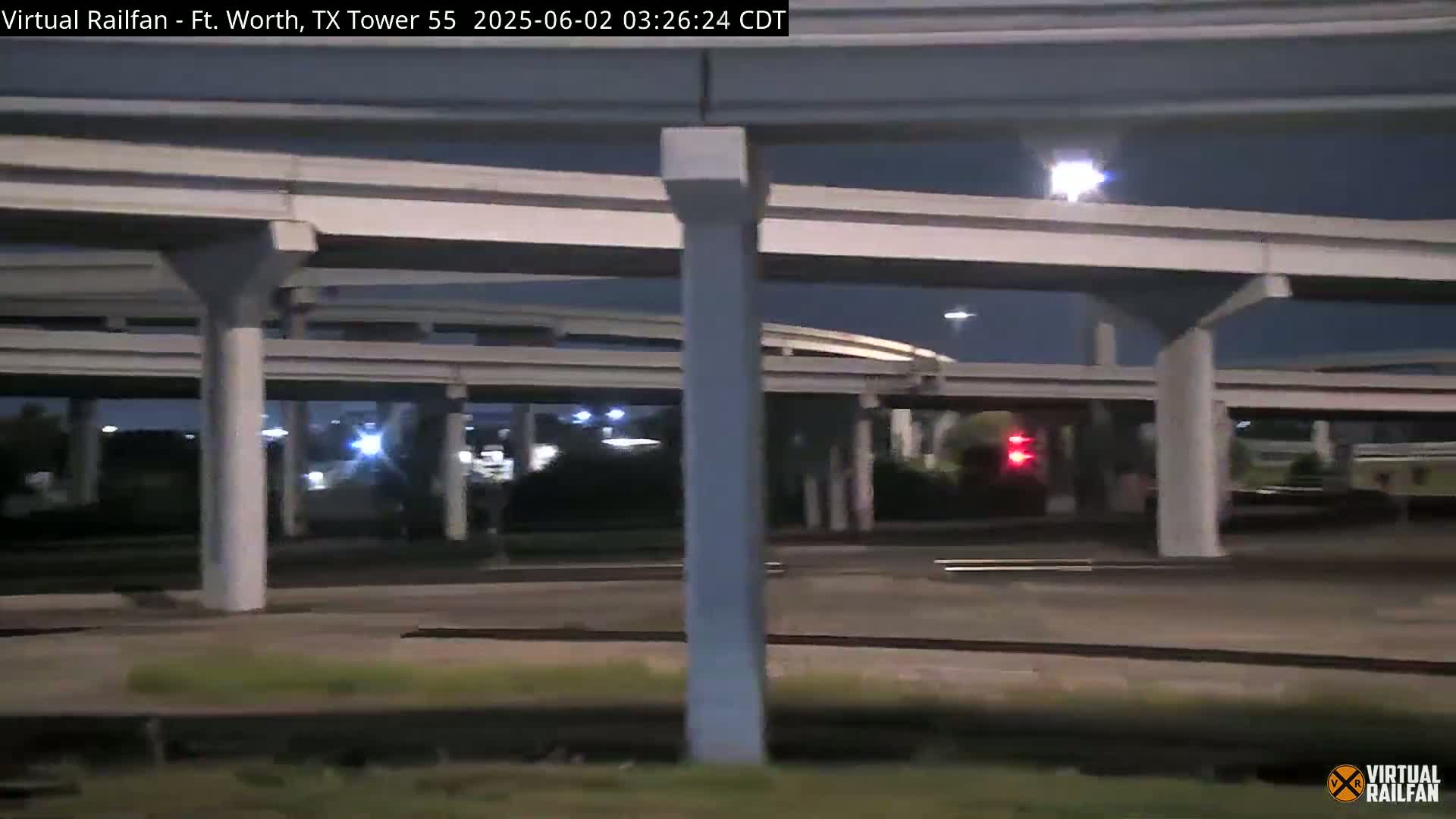 A nighttime view of a highway overpass and surrounding area under a dark sky.