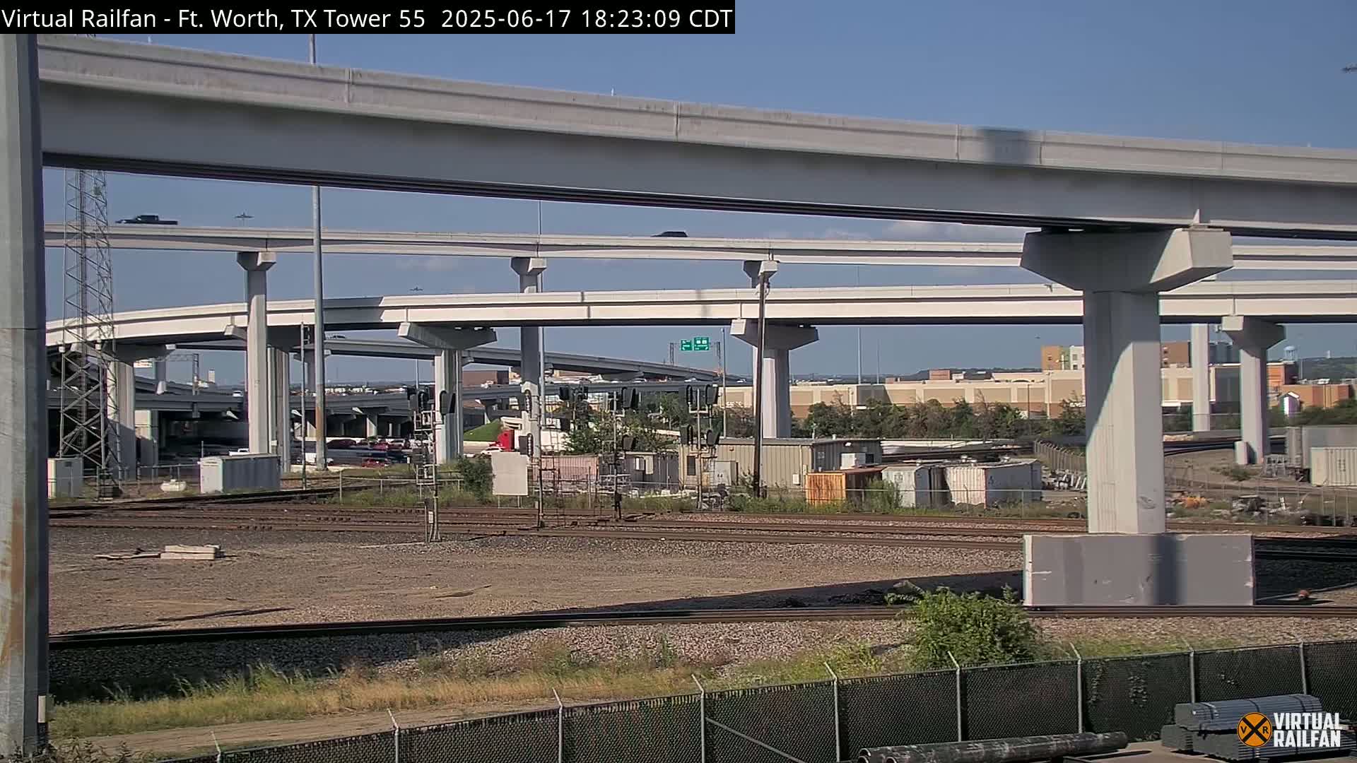 A view of a large highway overpass and railroad tracks on a sunny day.