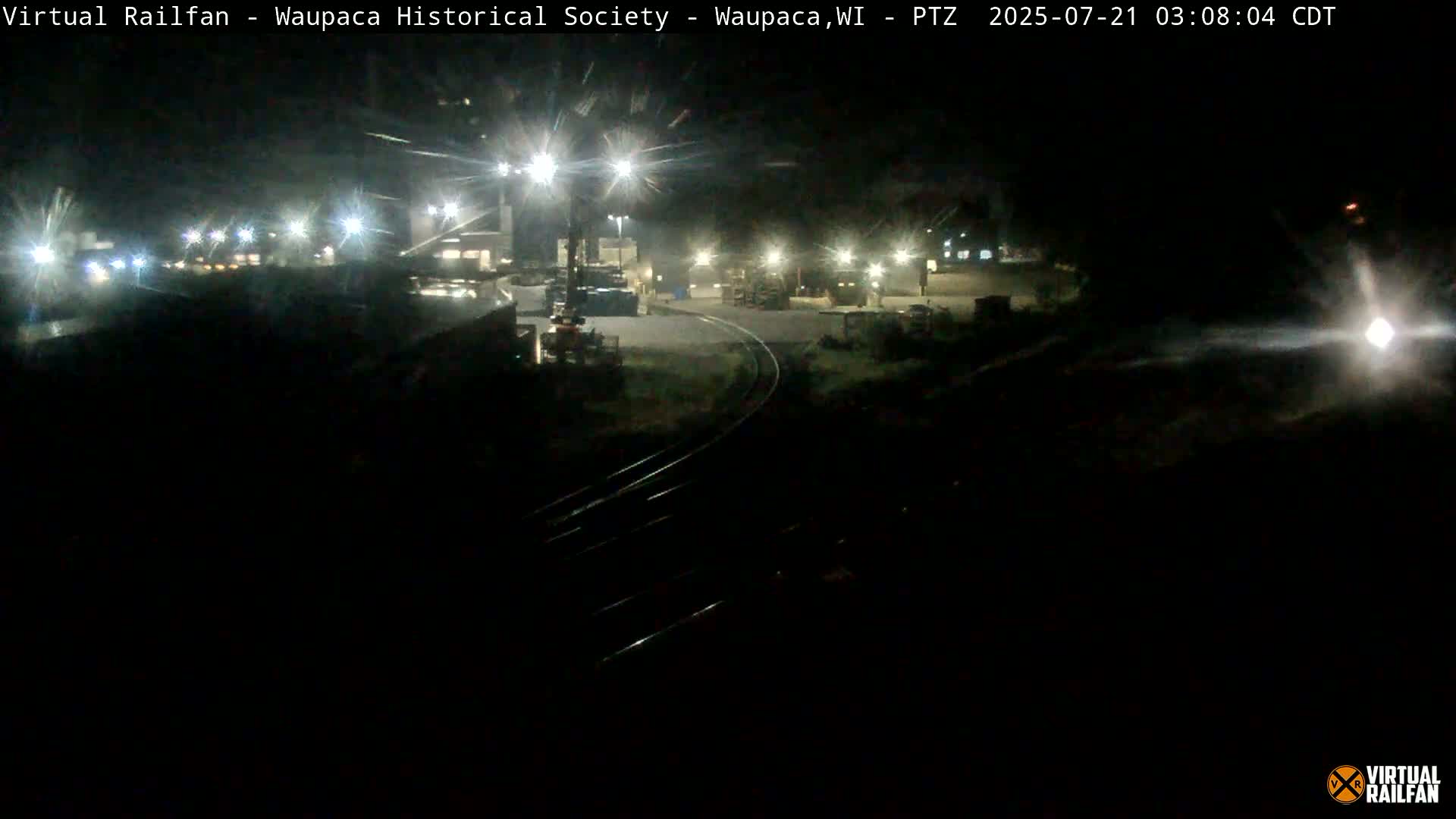 A nighttime view of a railway switching yard with several lights illuminating the area.