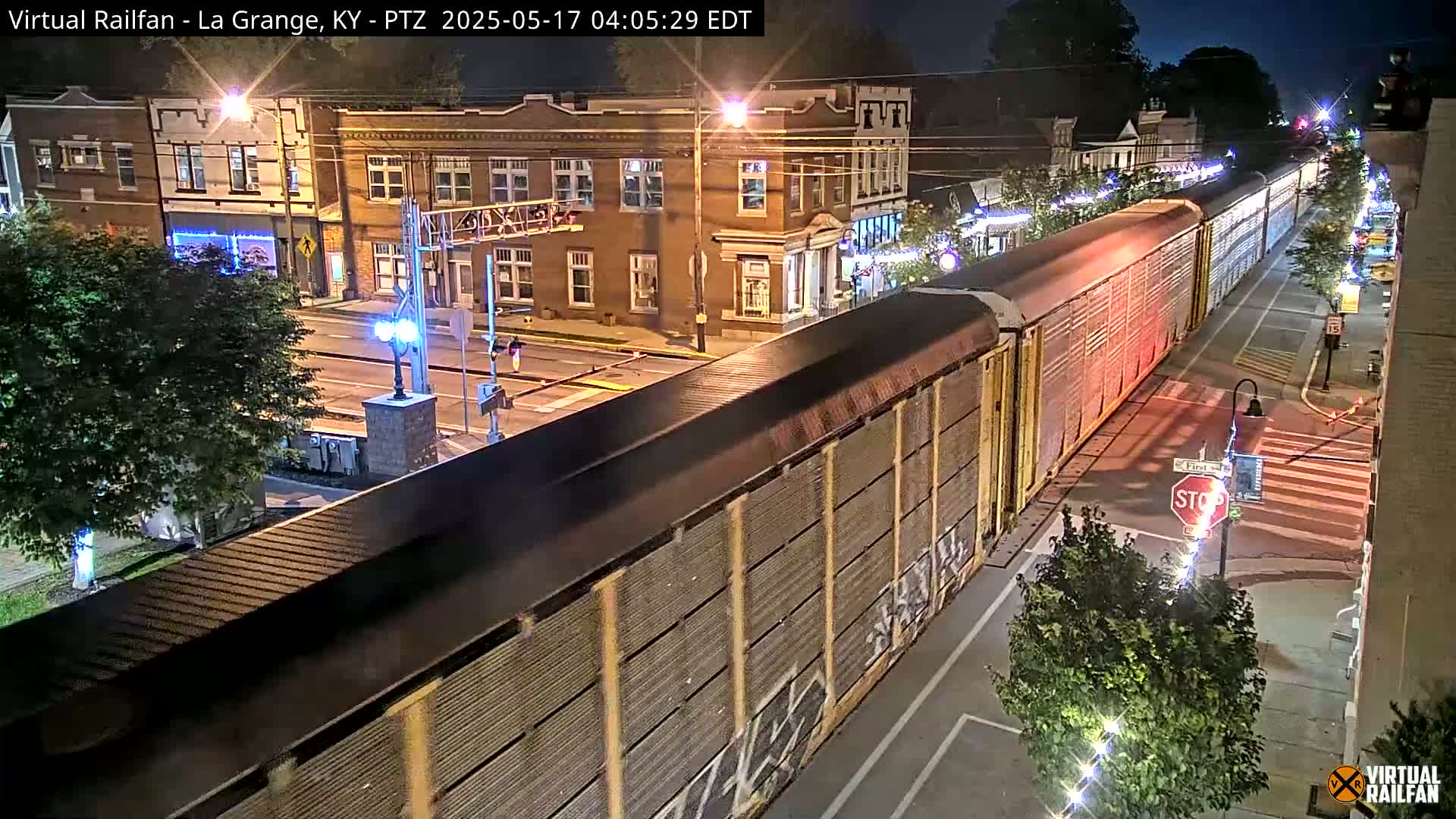A long freight train passes through a small town at night, under clear skies.