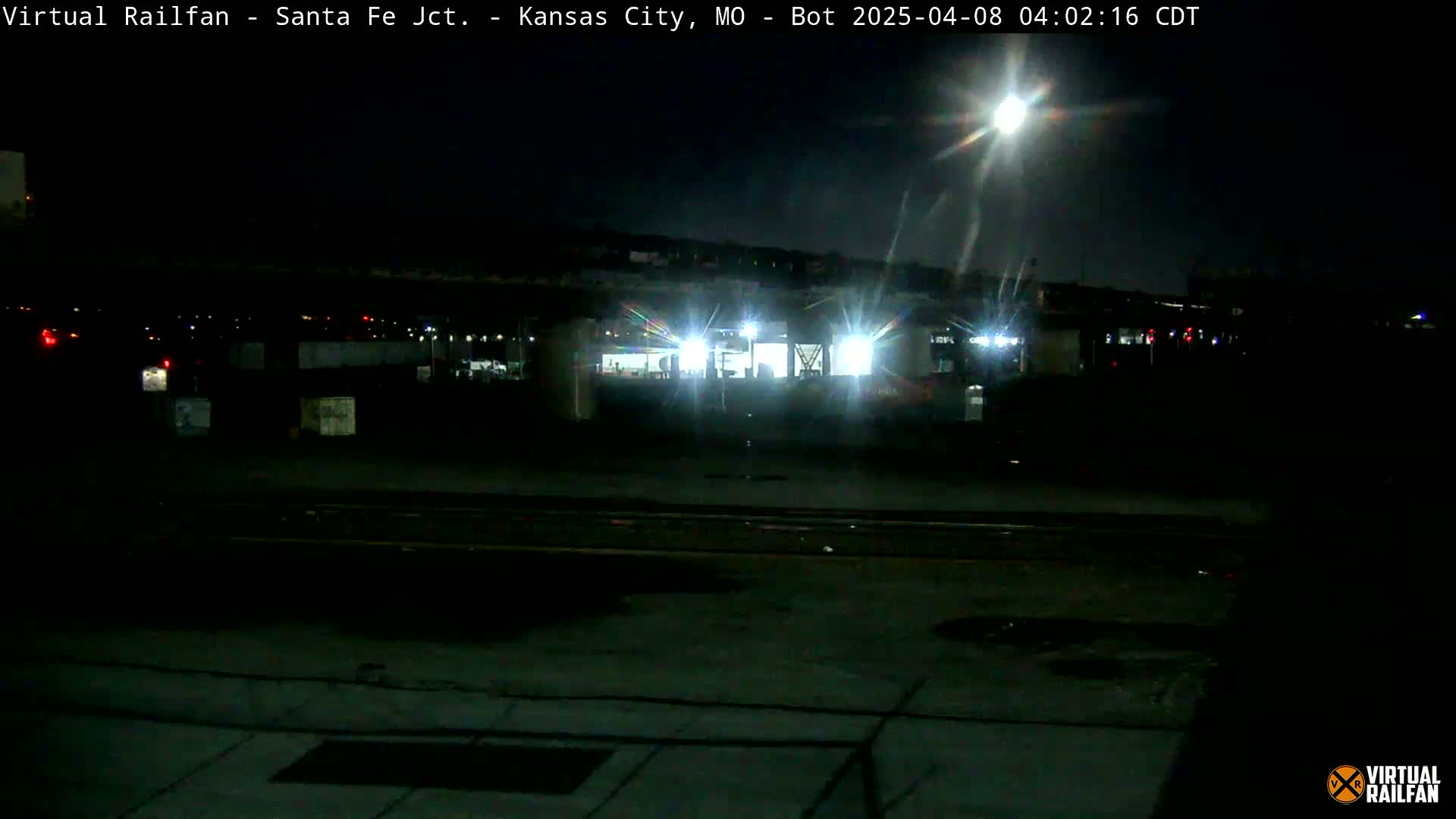 A nighttime view of a brightly lit rail yard under a bright moon.
