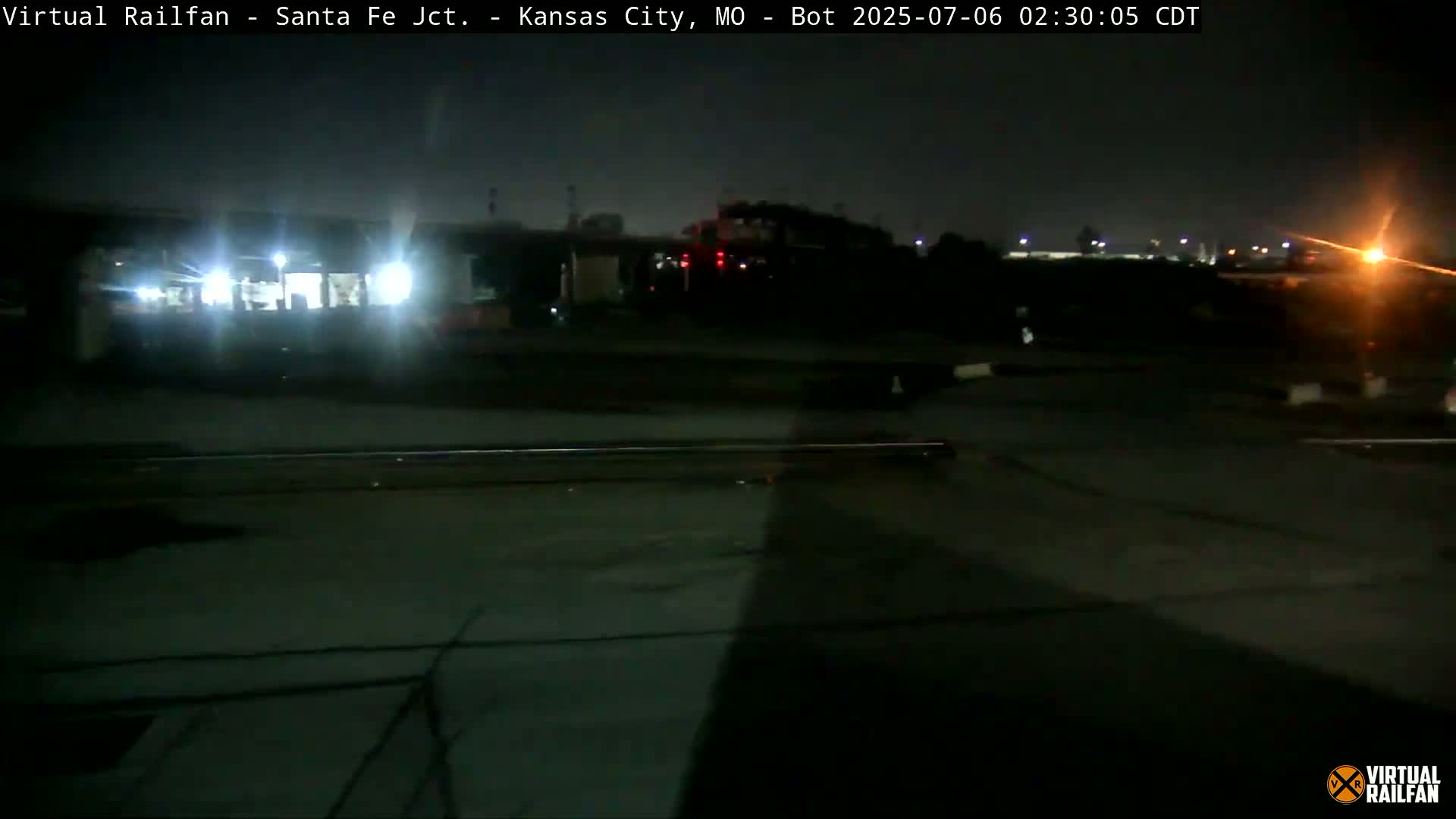A nighttime view of a train at a rail yard, under a dark sky.
