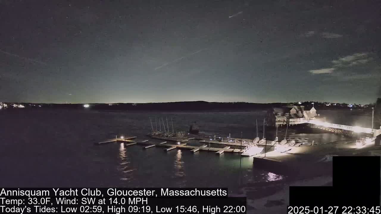 A nighttime view of a marina with docked sailboats under a clear, starry sky, with a southwest wind.