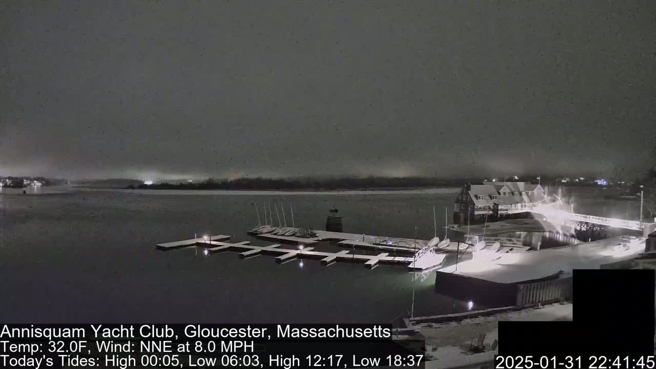 A snow-covered marina with boats docked at night under a dark, snowy sky.