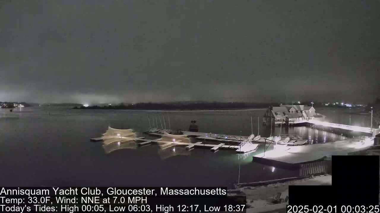 A snow-covered marina with boats docked at night under a dark, overcast sky.