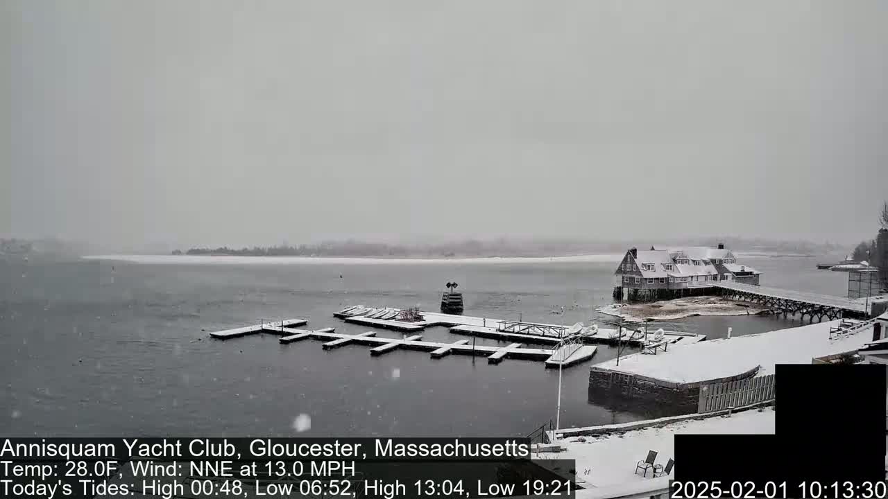 A snow-covered yacht club and marina are visible on a gray, snowy day.