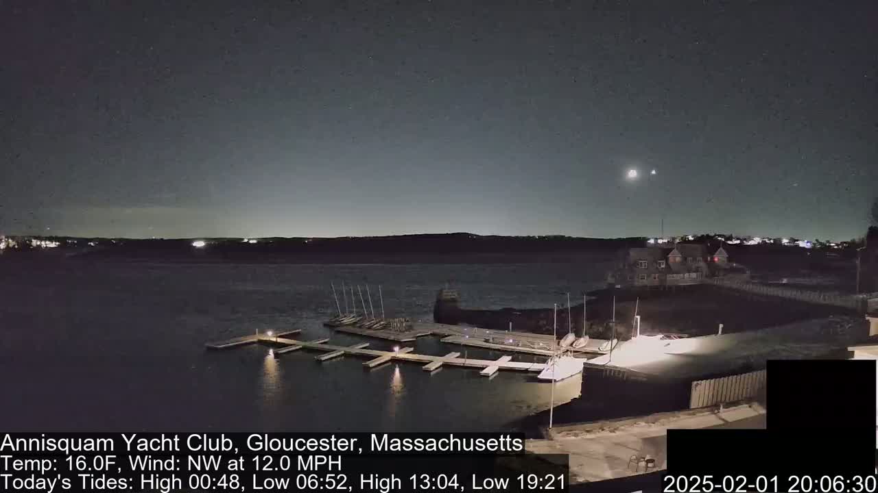 A nighttime view of a marina with several docked boats under a clear, dark sky with a few visible stars and a northwest wind.