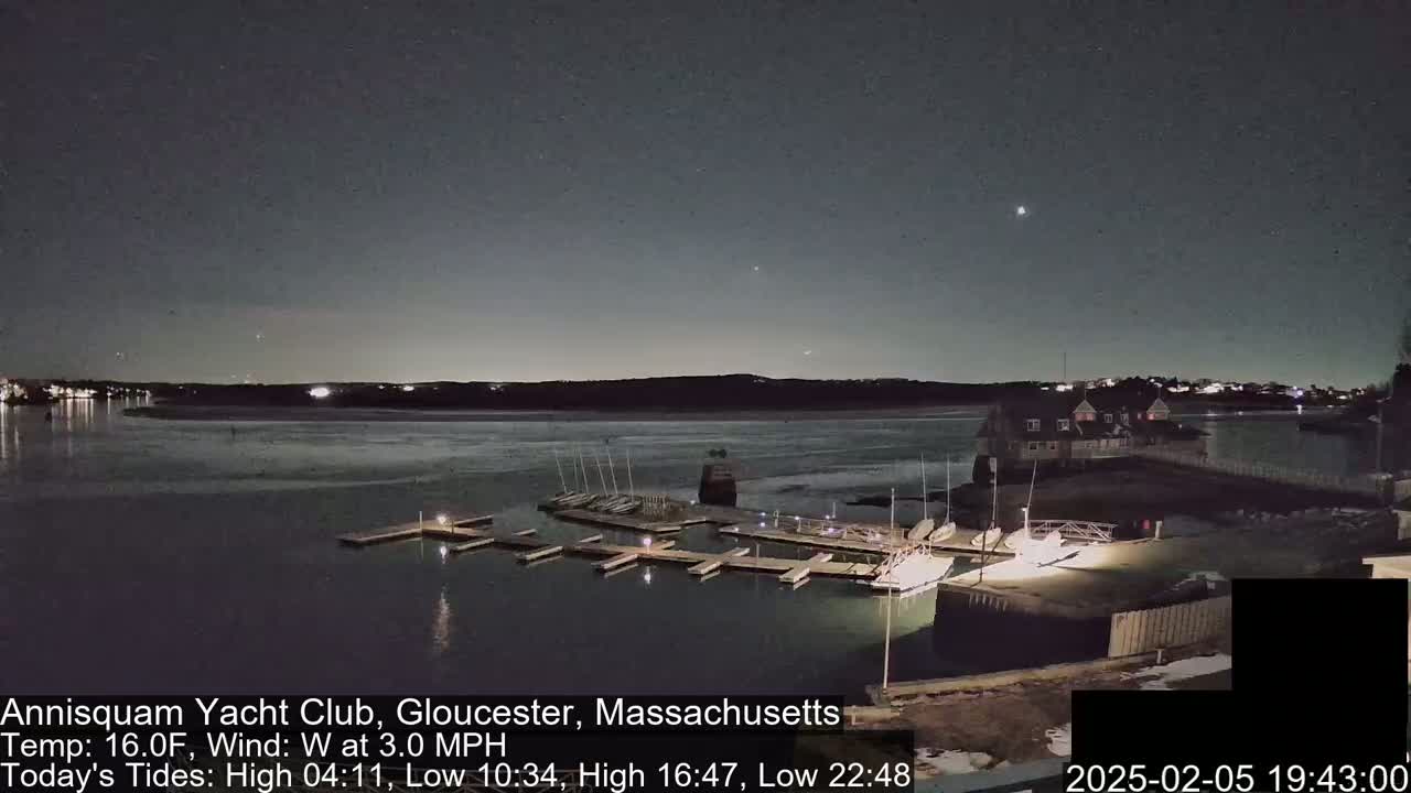 A nighttime view of a marina with boats docked under a clear, dark sky.