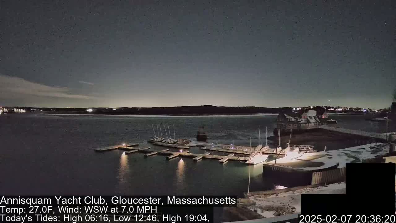 A nighttime view of a marina with docked sailboats under a dark, mostly clear sky.