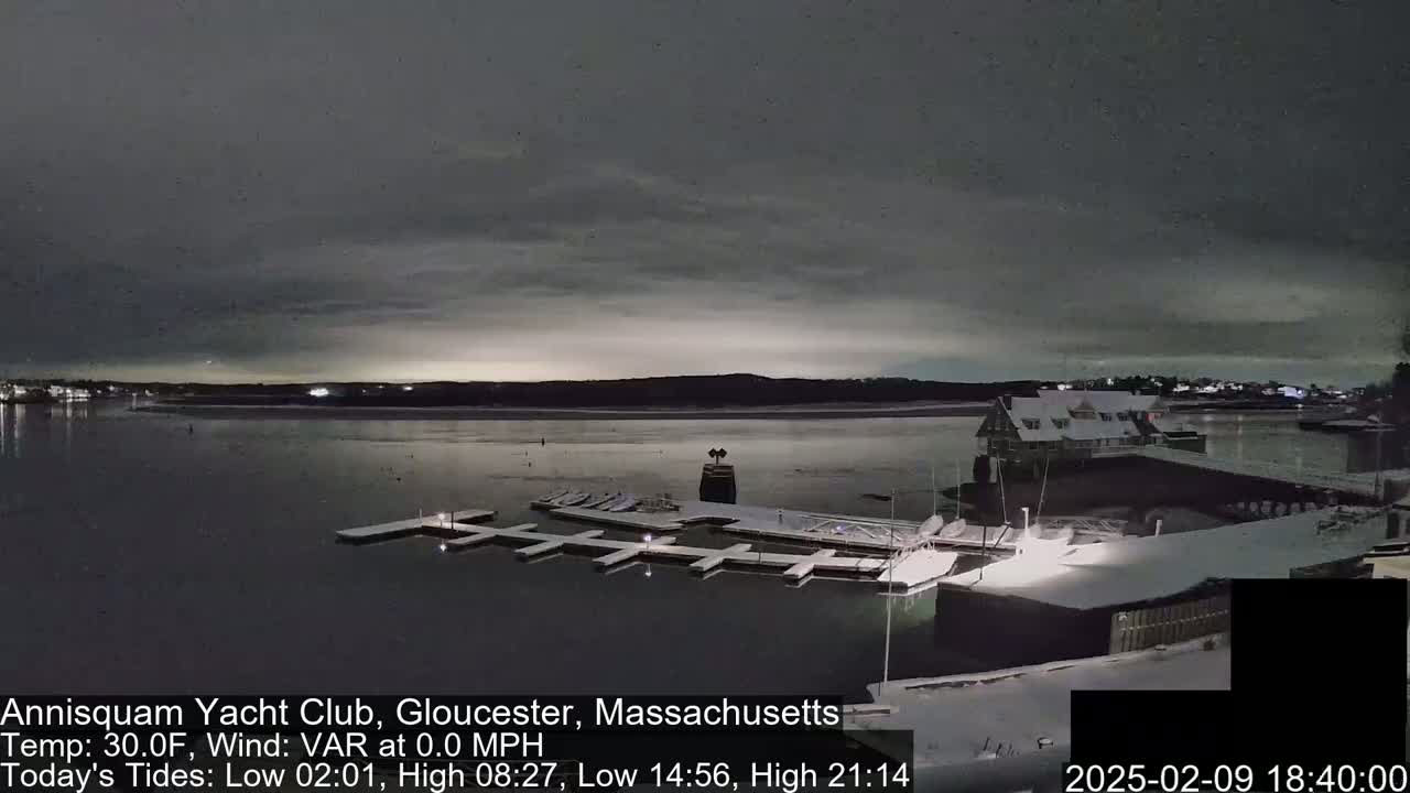A snow-covered marina with boats docked under a dark, overcast sky.