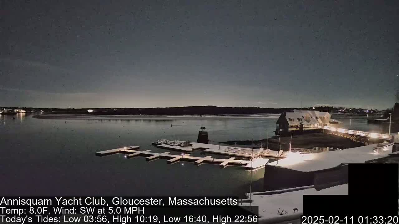 A snow-covered marina with boats docked at night under a dark, clear sky.