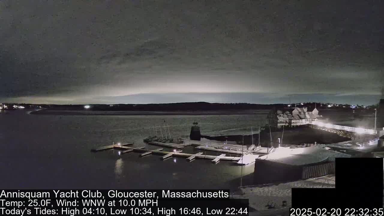 A nighttime view of a marina with docked boats under a dark, cloudy sky.