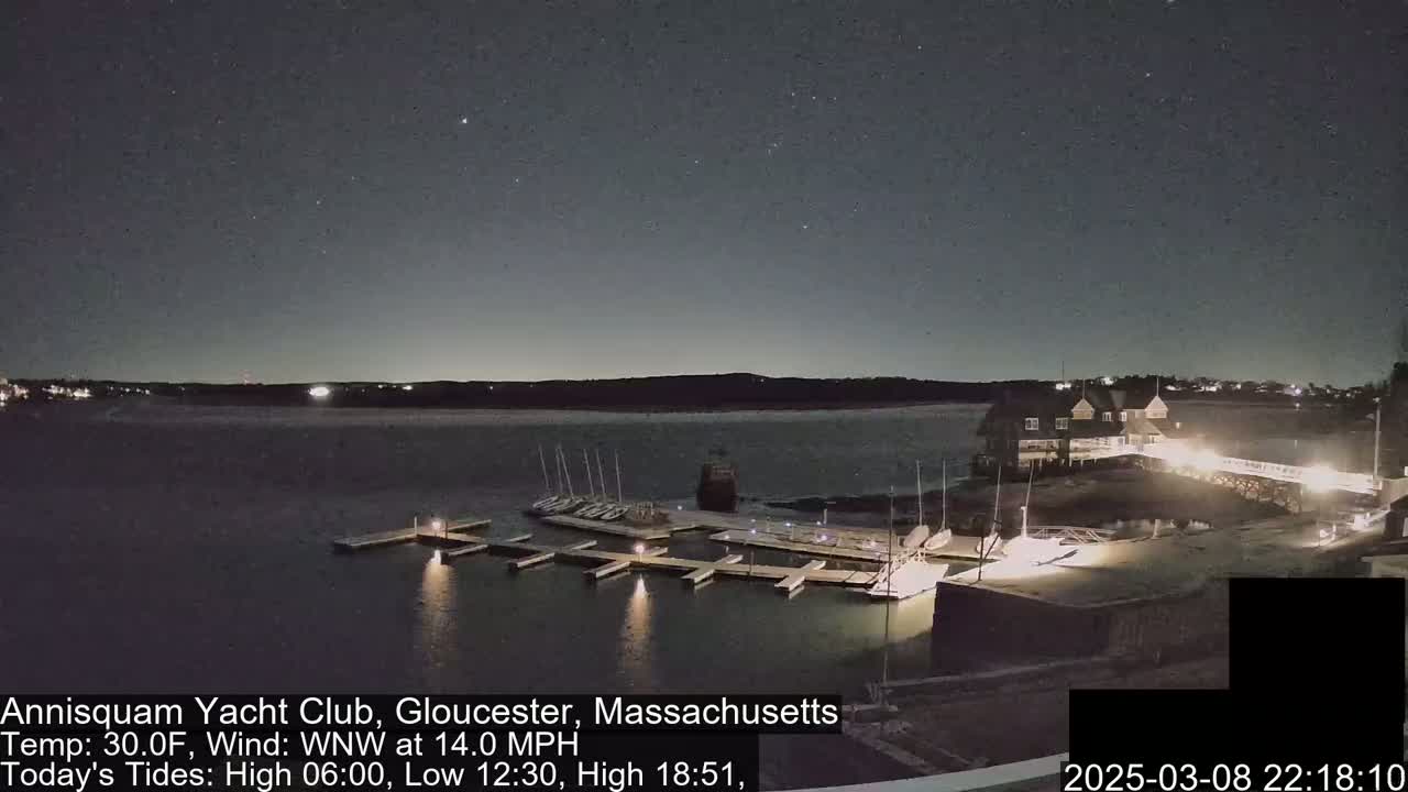 A nighttime view of a yacht club marina with several boats docked under a clear, starry sky.