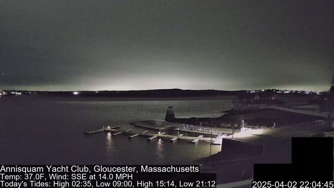A nighttime view of a marina with boats docked under a dark, overcast sky.
