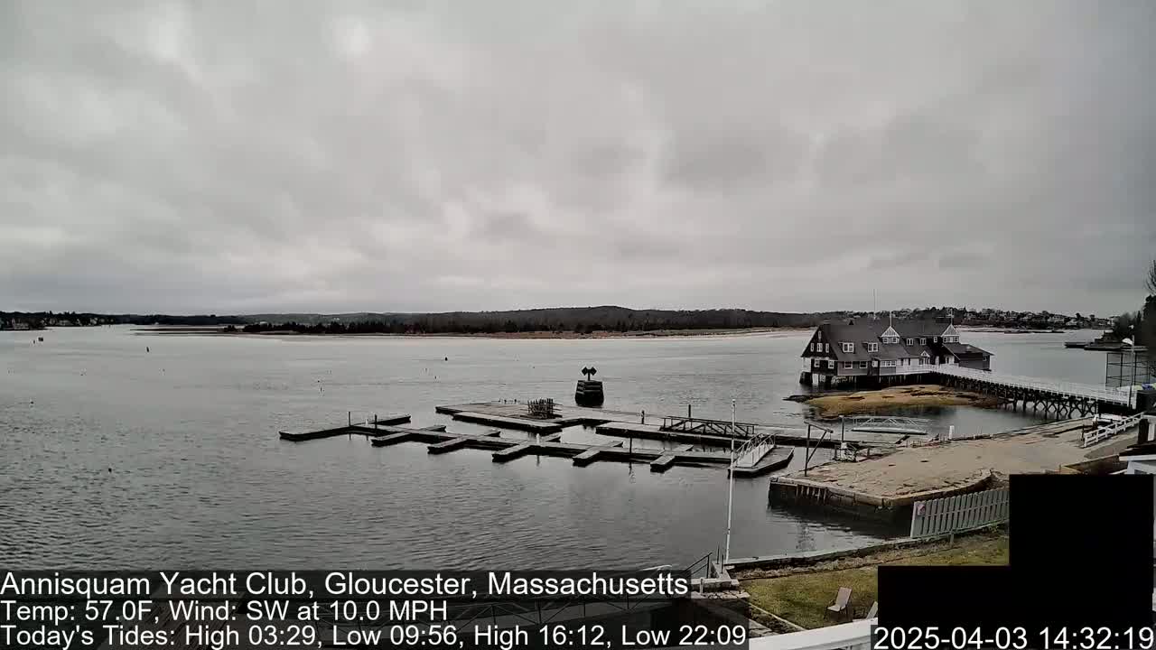 A calm body of water with a marina and a large clubhouse under an overcast sky.