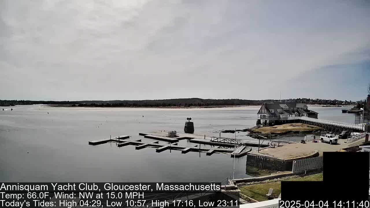 A calm bay with a marina and a clubhouse under an overcast sky.