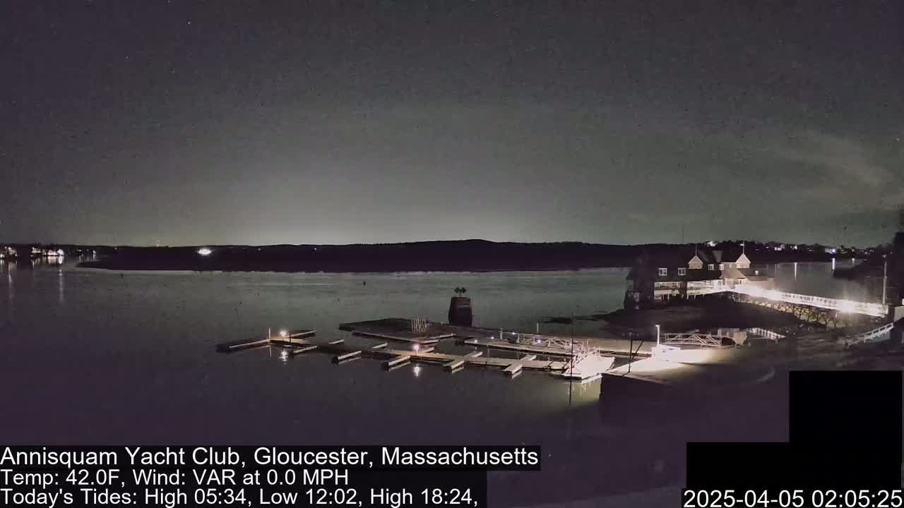 A nighttime view of a marina with calm water, under a dark sky with a few visible stars.