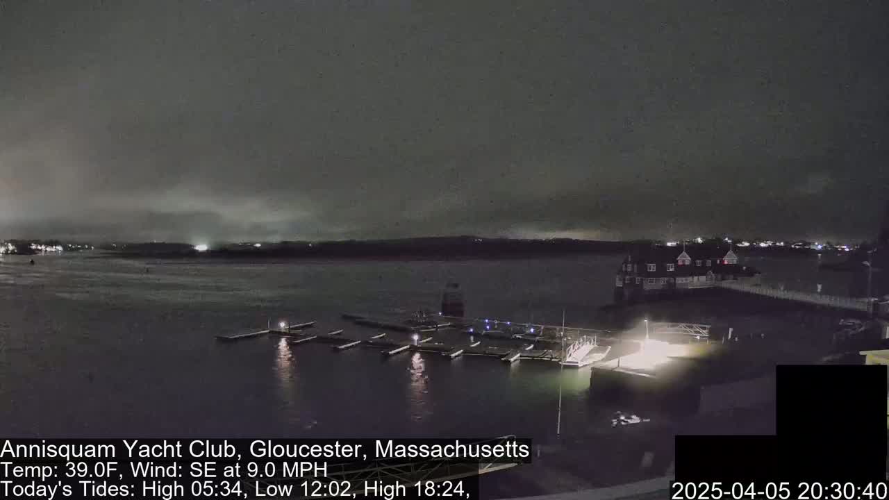 A nighttime view of a marina with docked boats under a dark, cloudy sky.