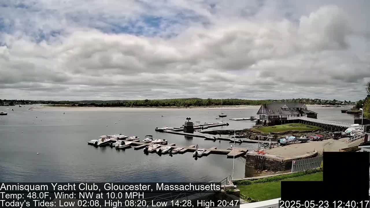 A marina with numerous boats docked under a partly cloudy sky.