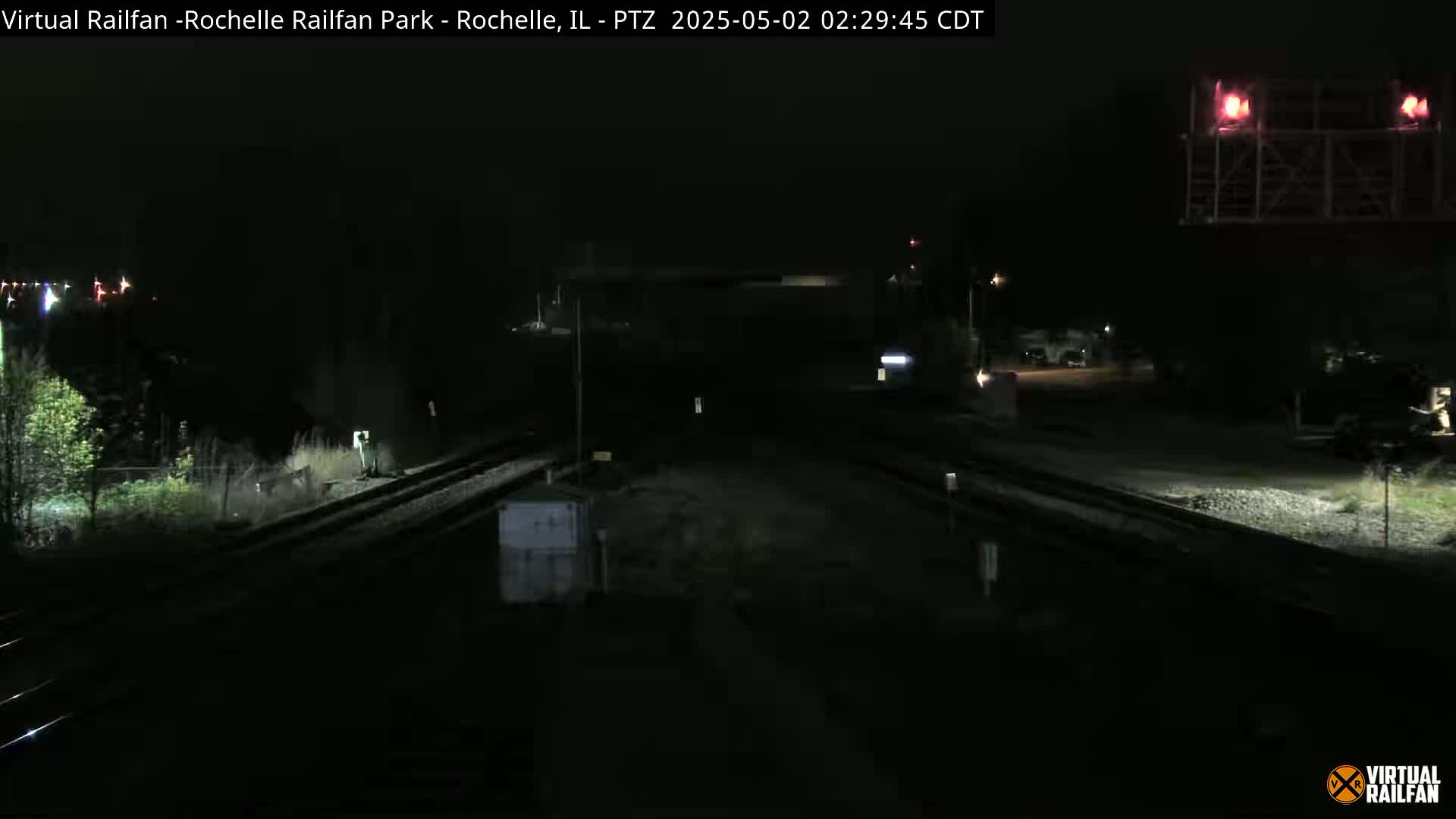 A nighttime view of railroad tracks and switching areas, illuminated by faint lights.