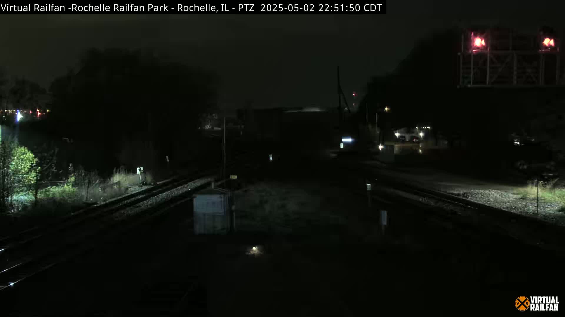 A nighttime view of a dark railway crossing with minimal lighting.