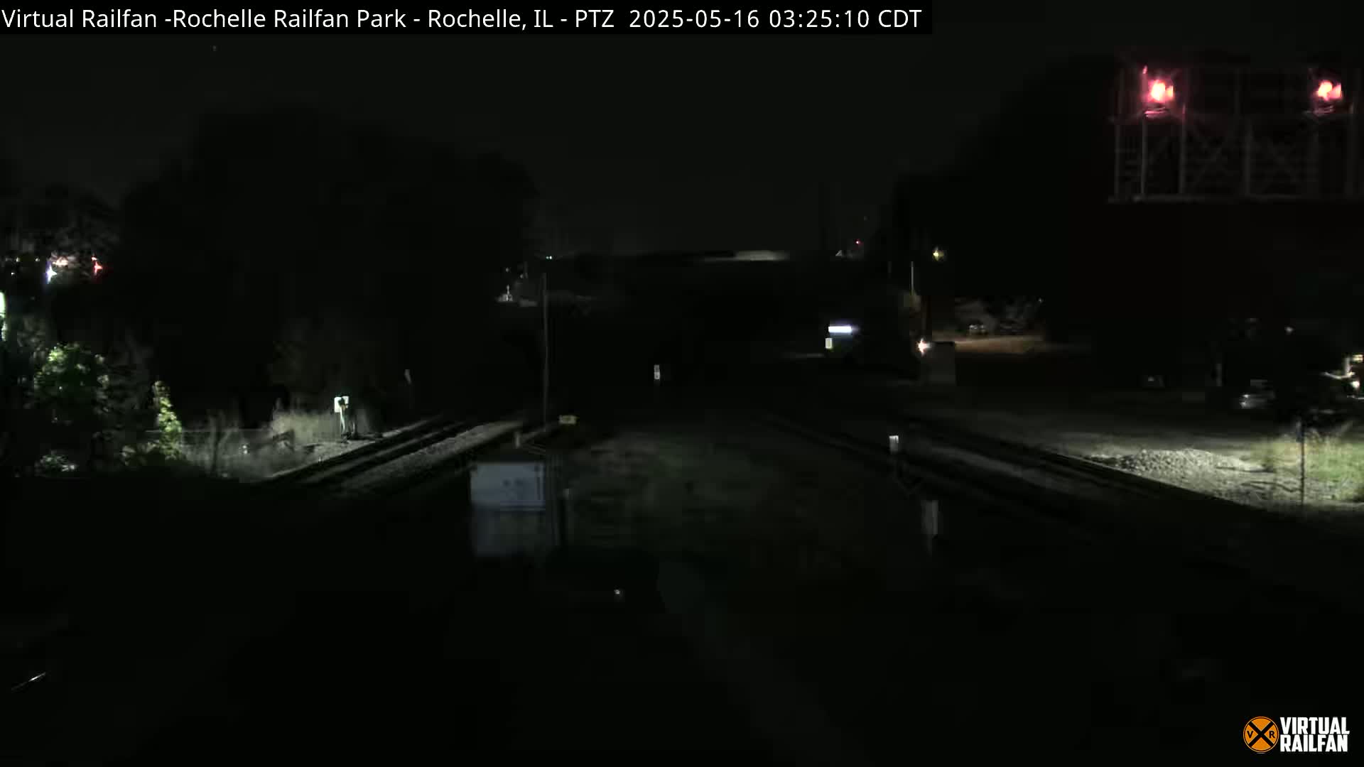 A nighttime view of railroad tracks and surrounding dark landscape.