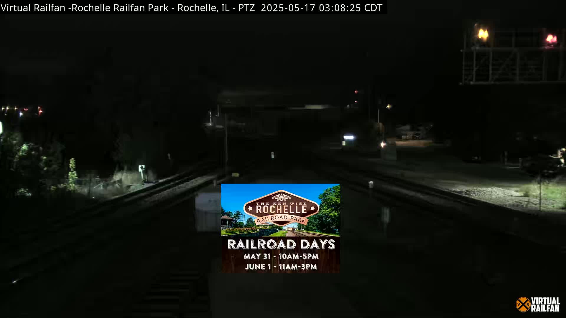 A nighttime, low-light view of a railroad crossing with train tracks intersecting.