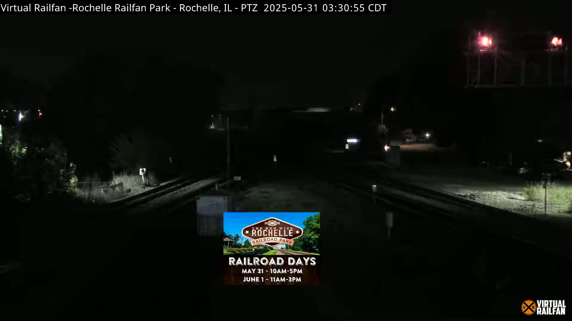 A nighttime view of railroad tracks and a dimly lit area, possibly a train station.