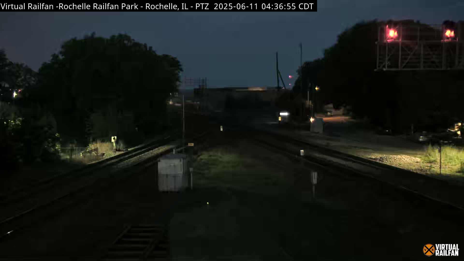 A nighttime view of railroad tracks and switching equipment under a dark sky.