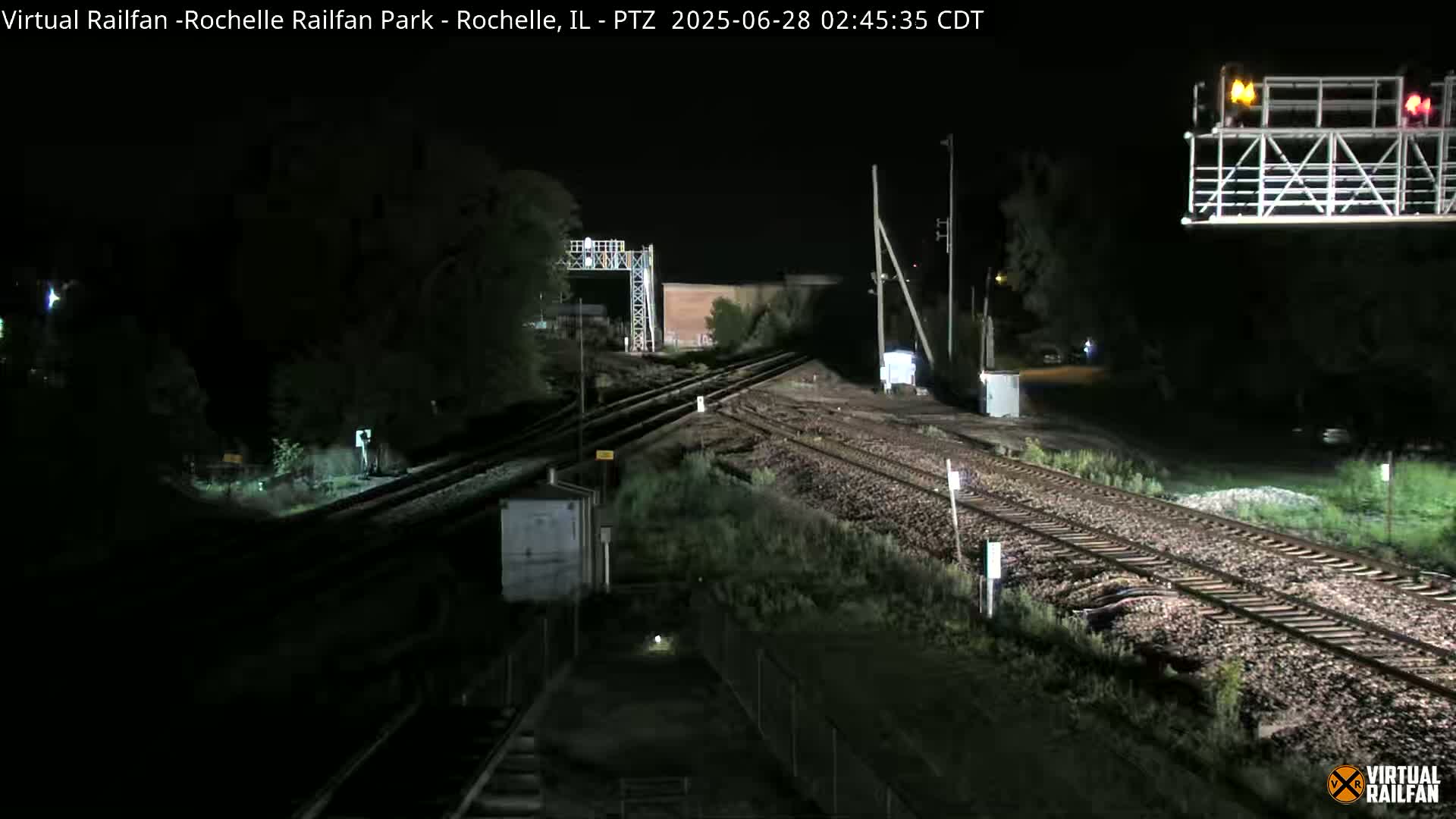 A nighttime view of railroad tracks and switching equipment, illuminated artificially.