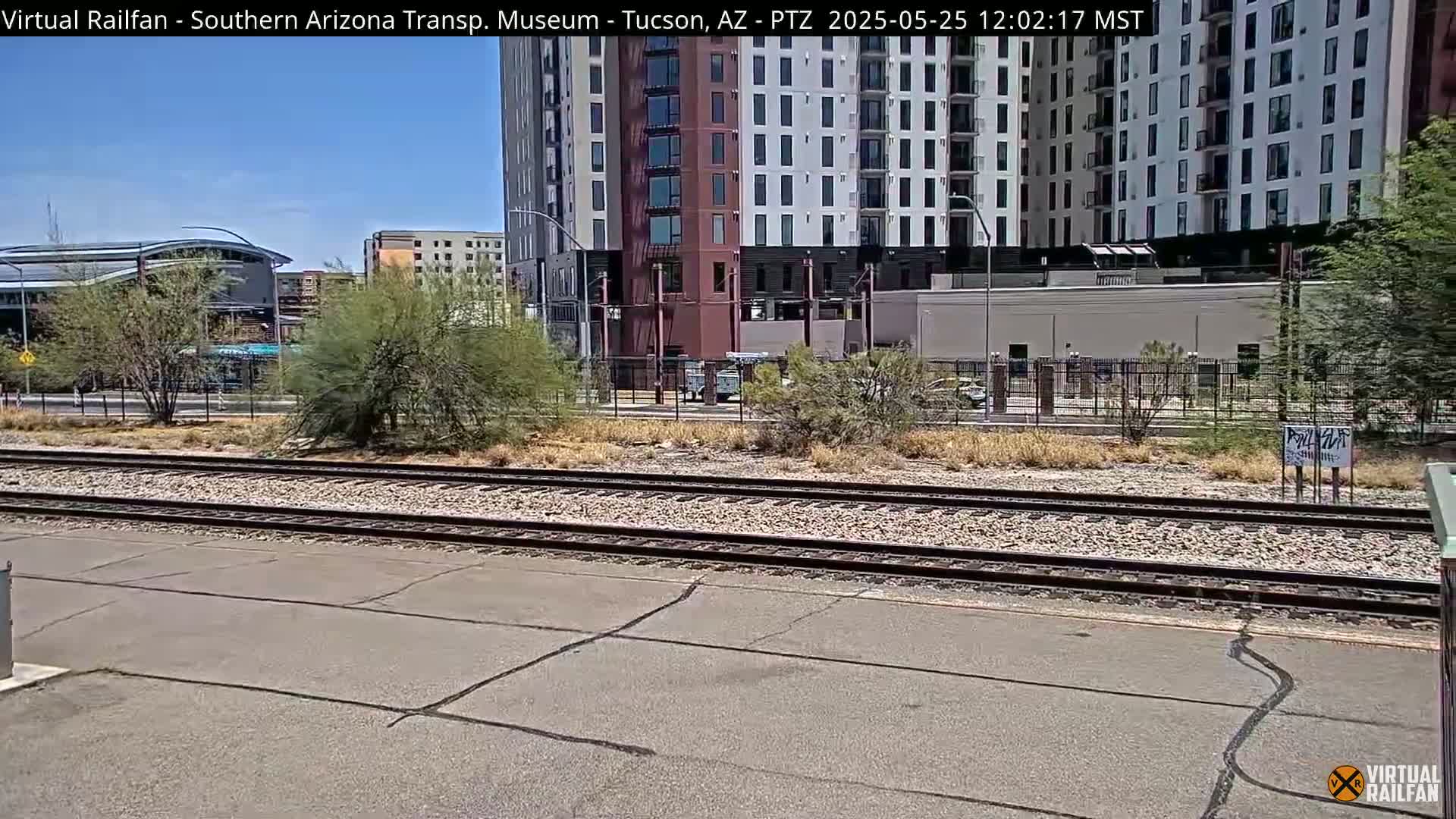 A view of railroad tracks in front of a tall apartment building on a sunny day.