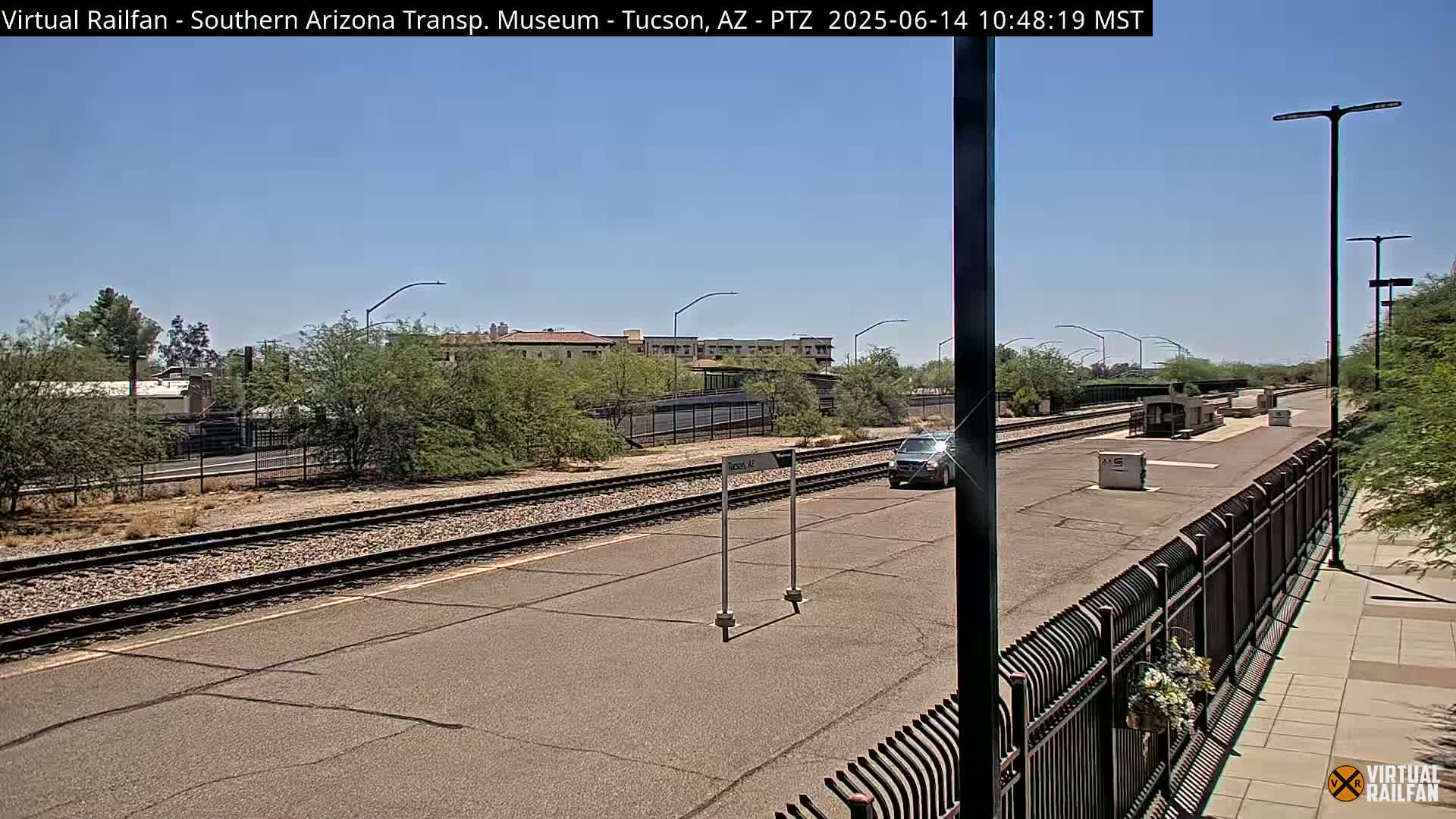 A train station platform with a single vehicle on a sunny day.