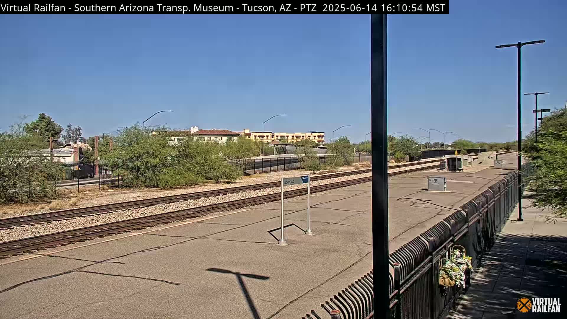 A train station platform with a single vehicle on a sunny day.