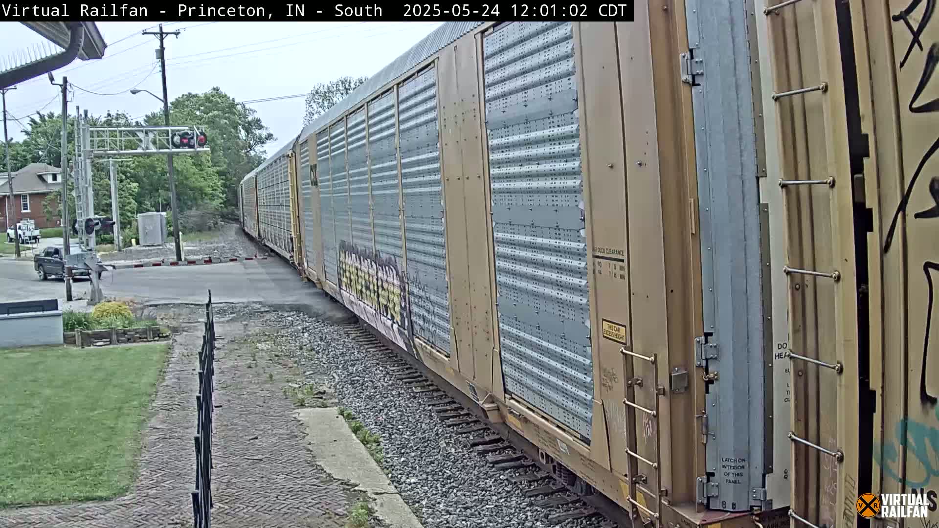 A long freight train passes a road crossing on an overcast day.