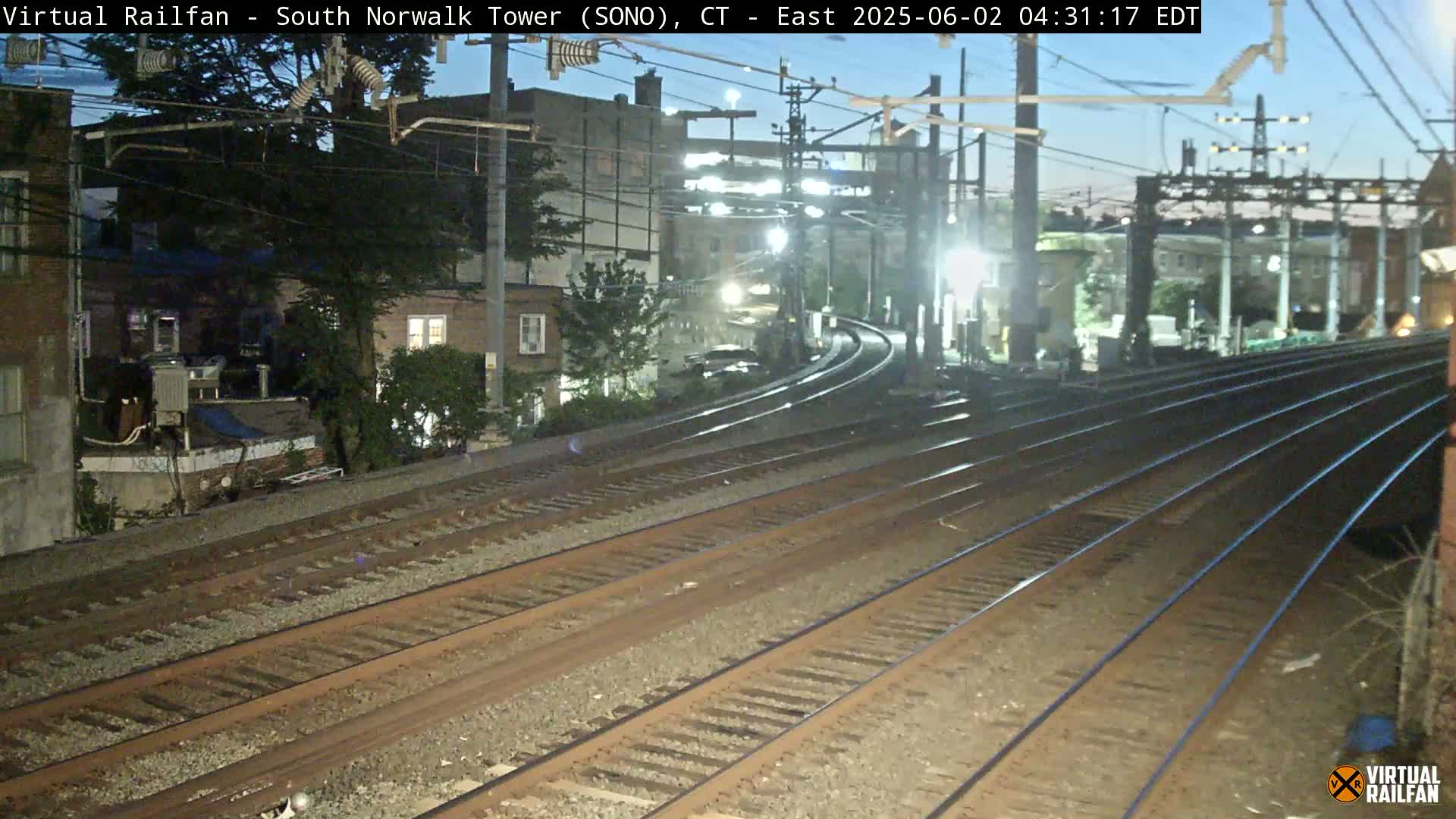Multiple sets of train tracks curve away from the camera under a twilight sky.
