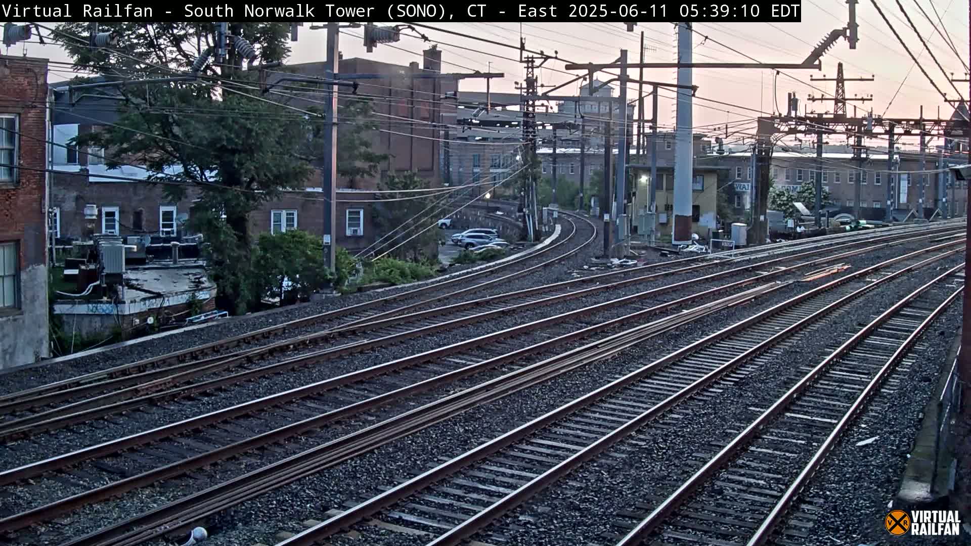 Several sets of train tracks curve gently through a cityscape at dusk.