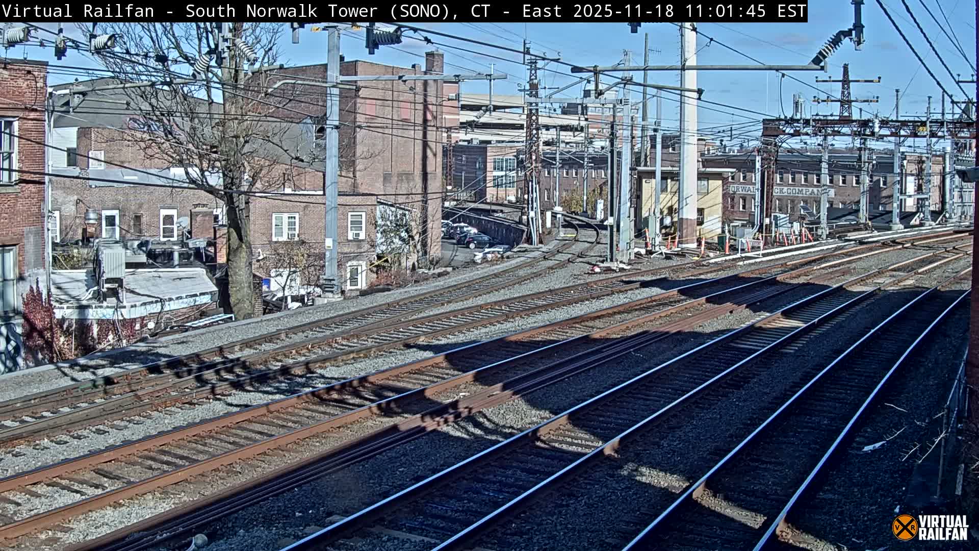 Multiple train tracks extend into the distance at night, curving slightly to the right past buildings and trees under artificial lighting.