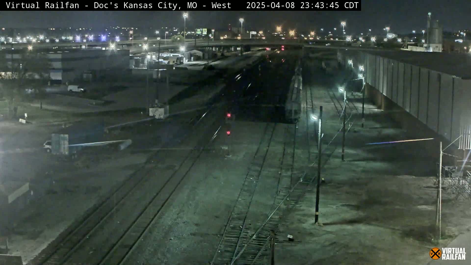 A nighttime view of railroad tracks and industrial buildings under clear skies.