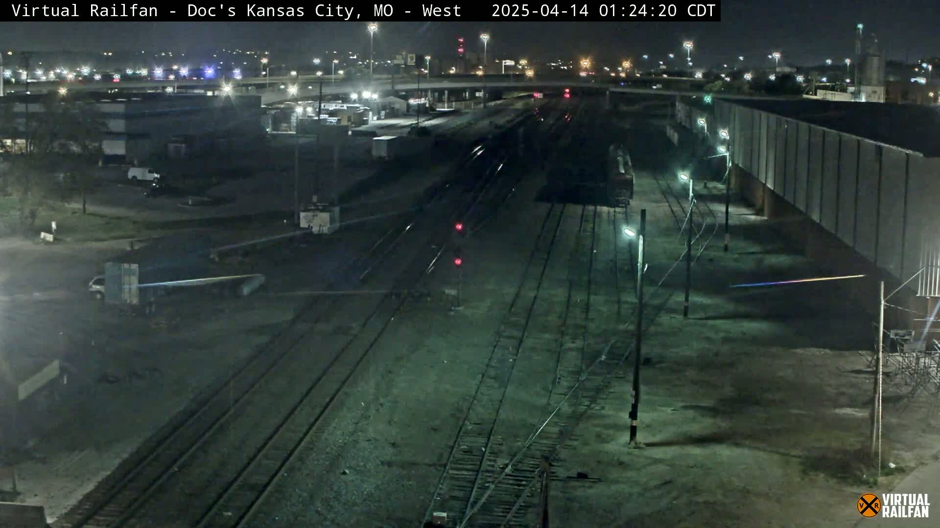 A nighttime view of railroad tracks and industrial buildings under clear skies.