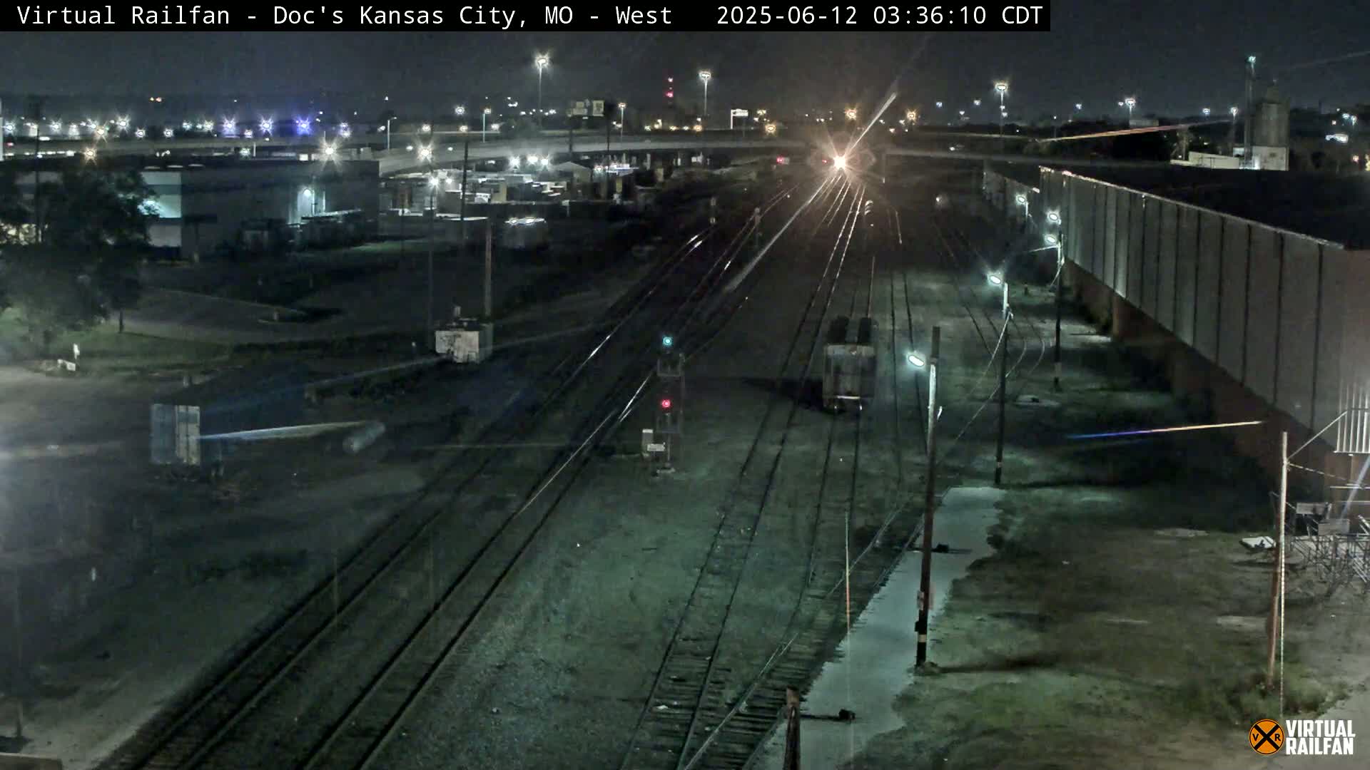 A nighttime view of railroad tracks and industrial buildings under clear skies.