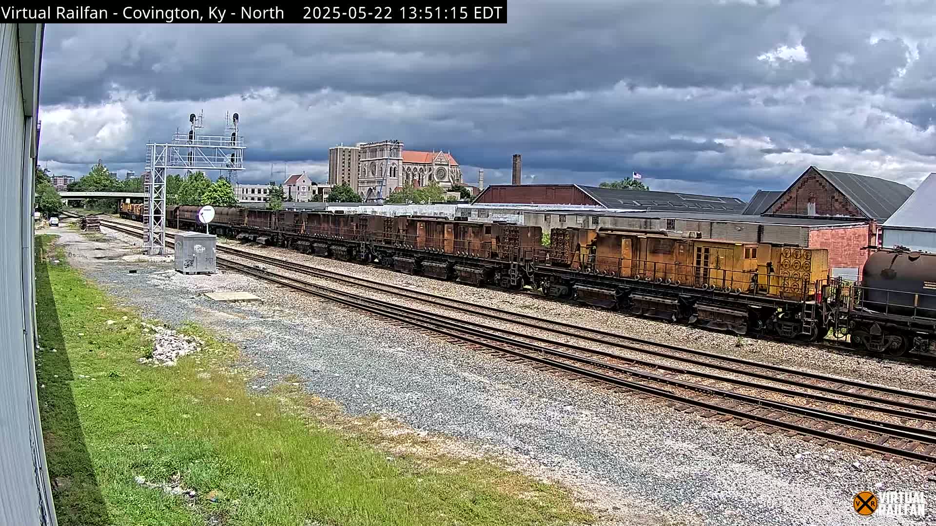 A long freight train sits on multiple train tracks under a cloudy sky.